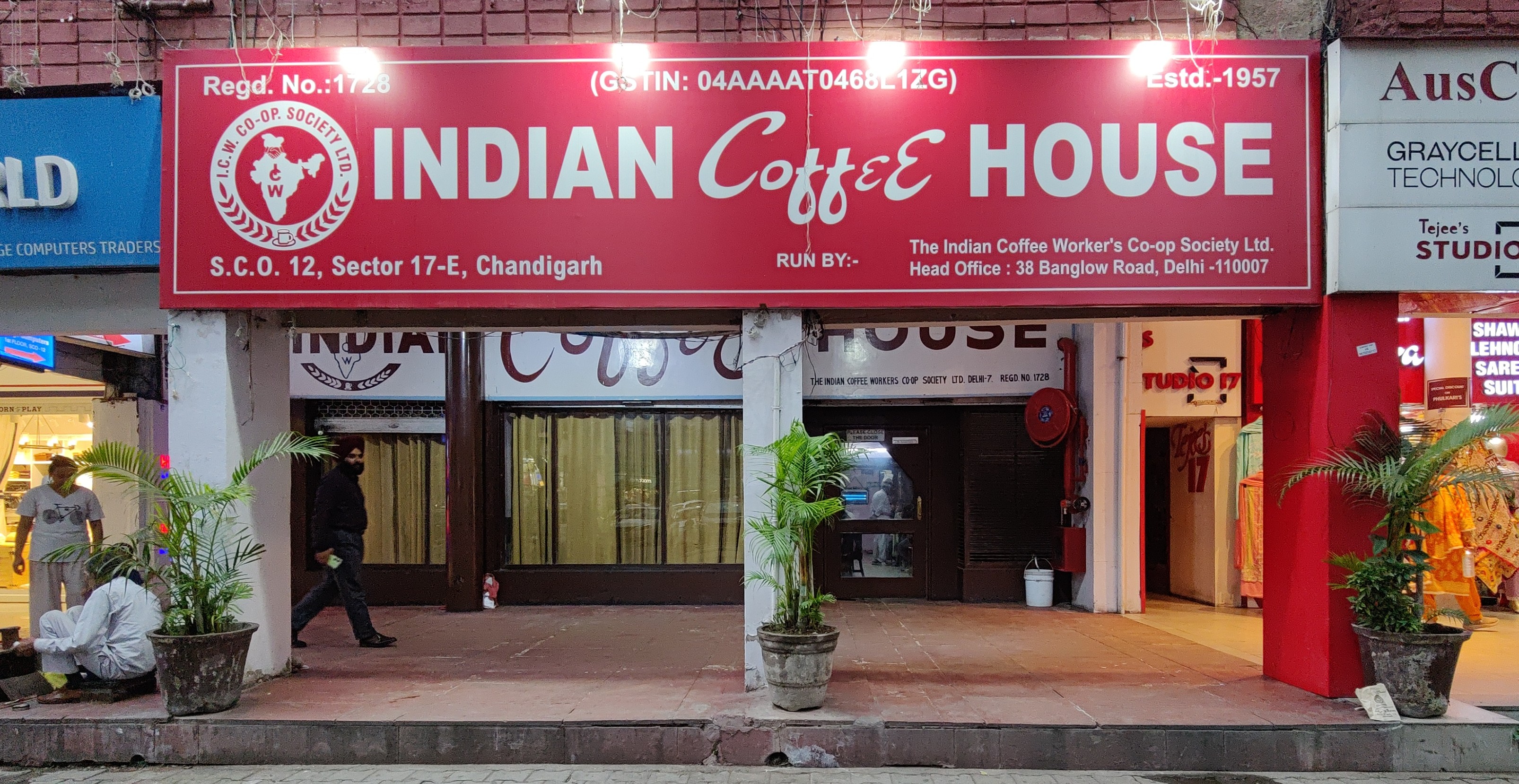 A board can be seen with "Indian Coffee House" written on it in a big font. A café can be seen behind the board. A board can be seen with "Indian Coffee House" written on it in a big font. A café can be seen behind the board.