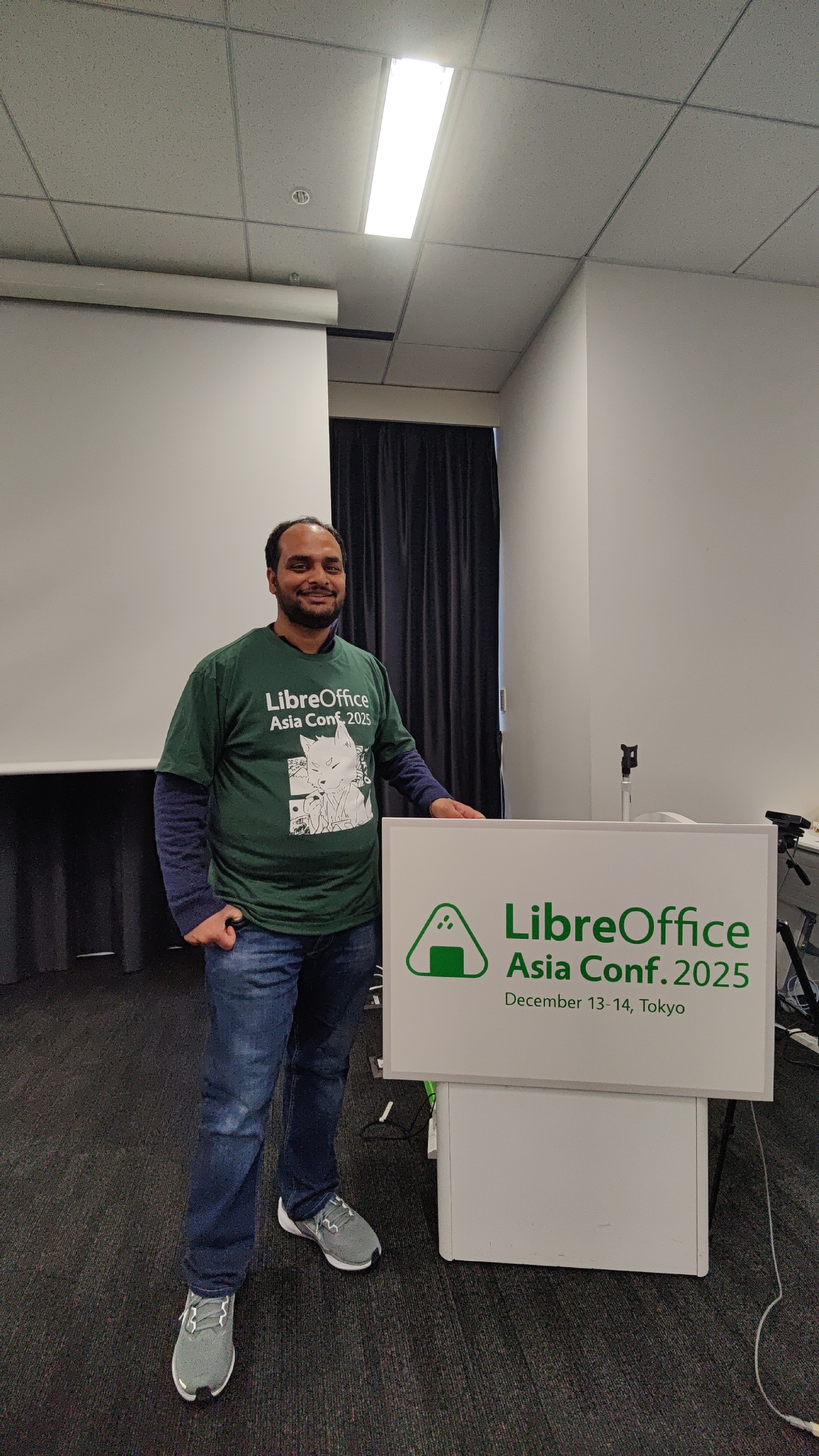 A person standing with a board saying "LibreOffice Asia Conf 2025".