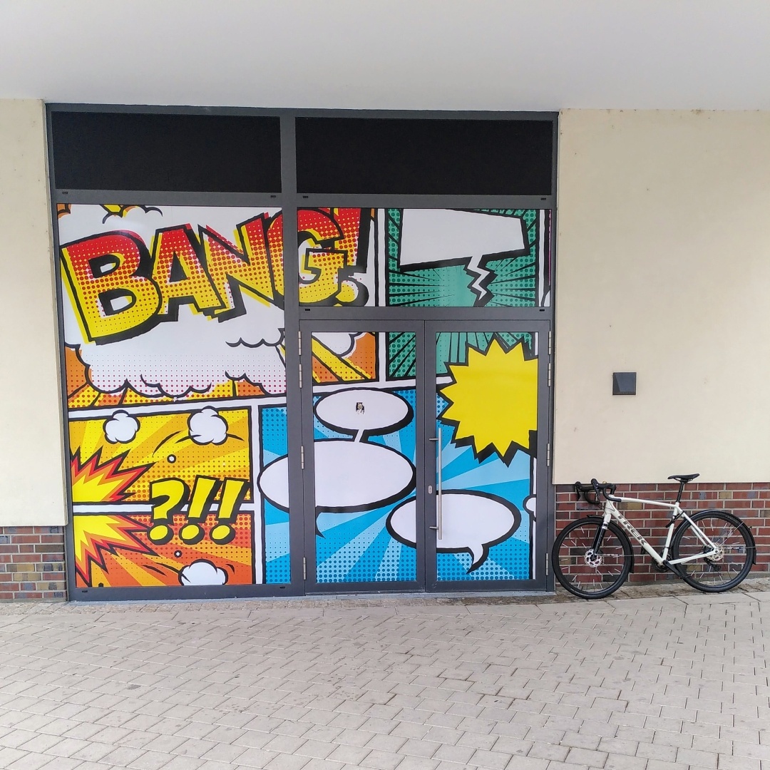 mein Gravelbike neben einer knallig bunt beklebten Fensterfront