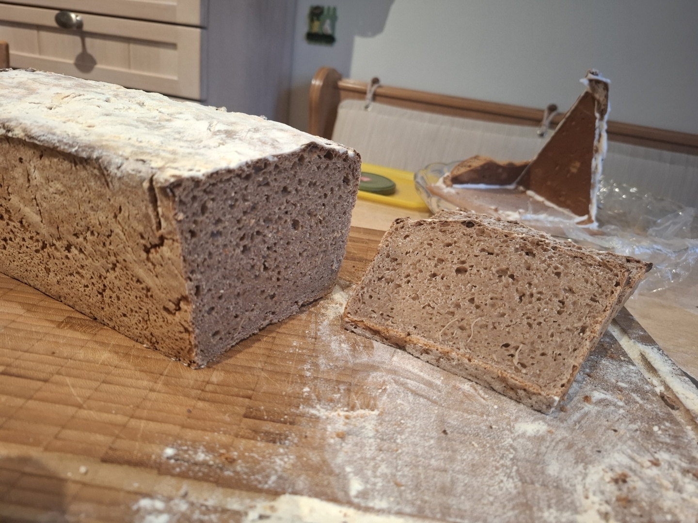 A tin loaf with a few cut slices on a flour dusted table.