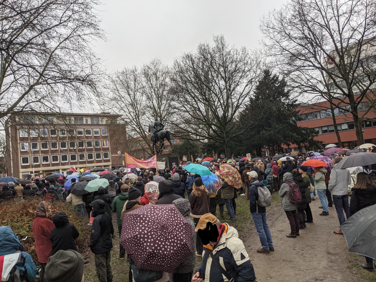 Zahlreiche Menschen mit Regenschirmen demonstrieren gegen Rechts.