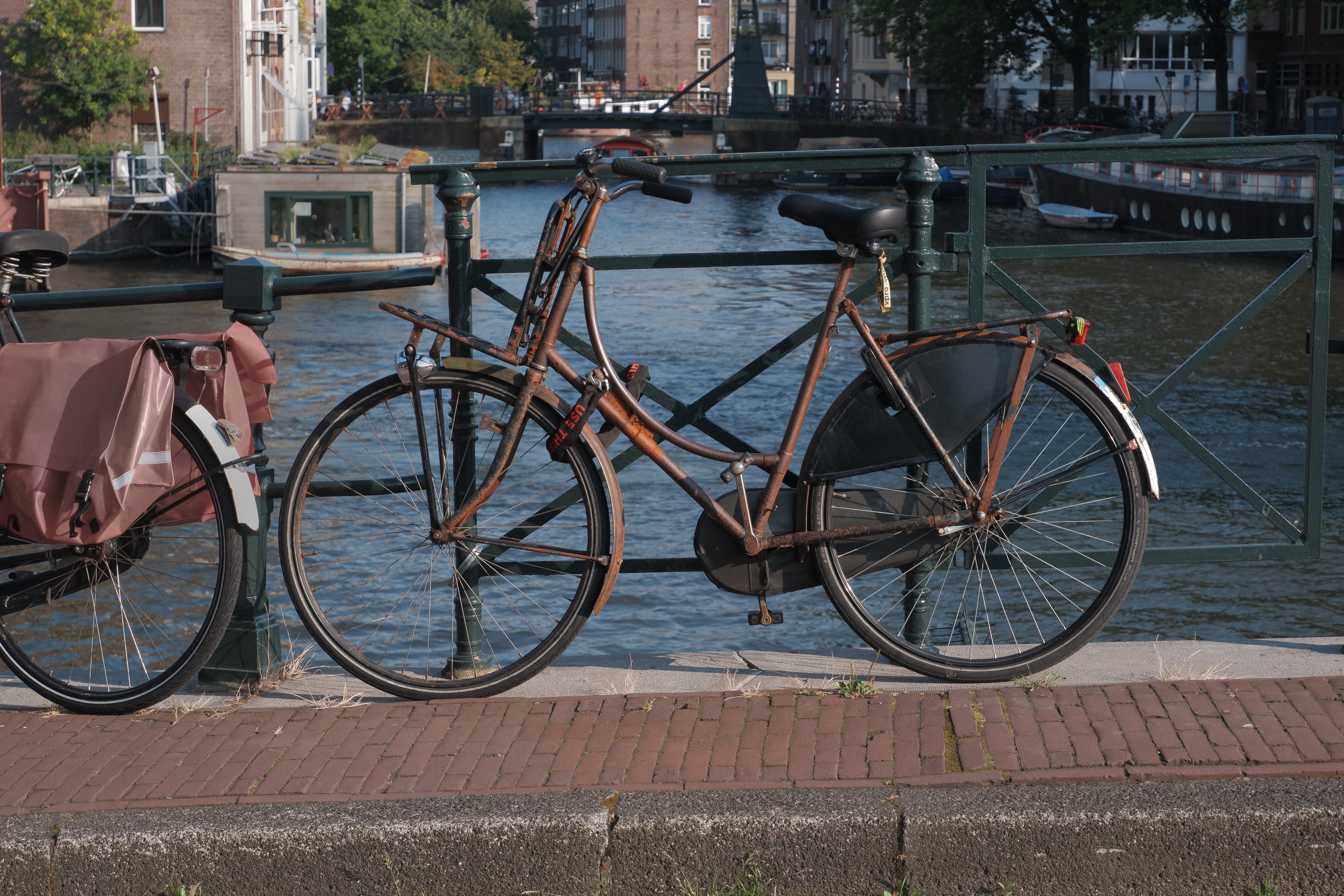 photo of a bicycle on a small bridge, locked to it, covered by rust.