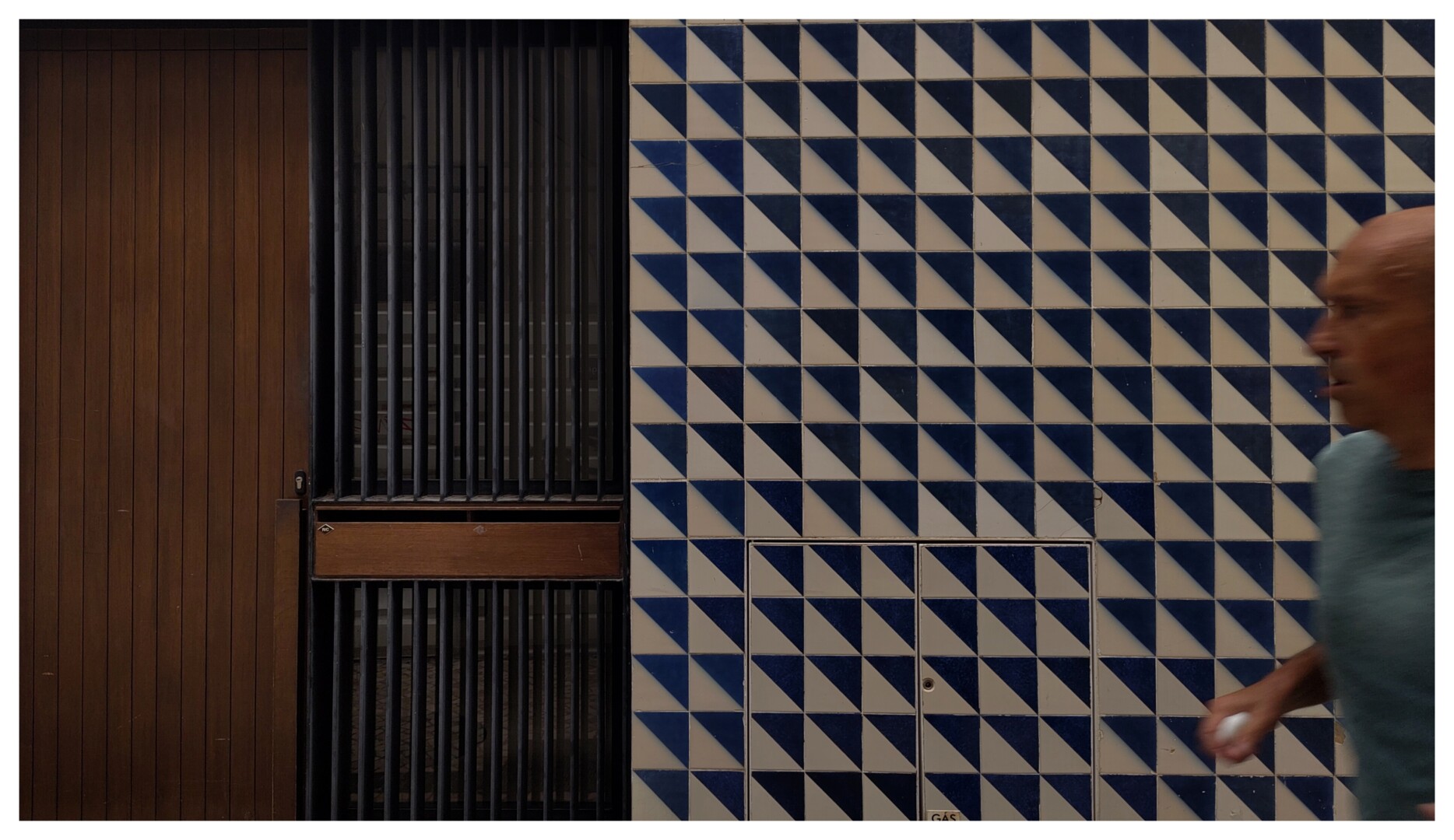 a blurry person runs over a blue and white tiled wall
